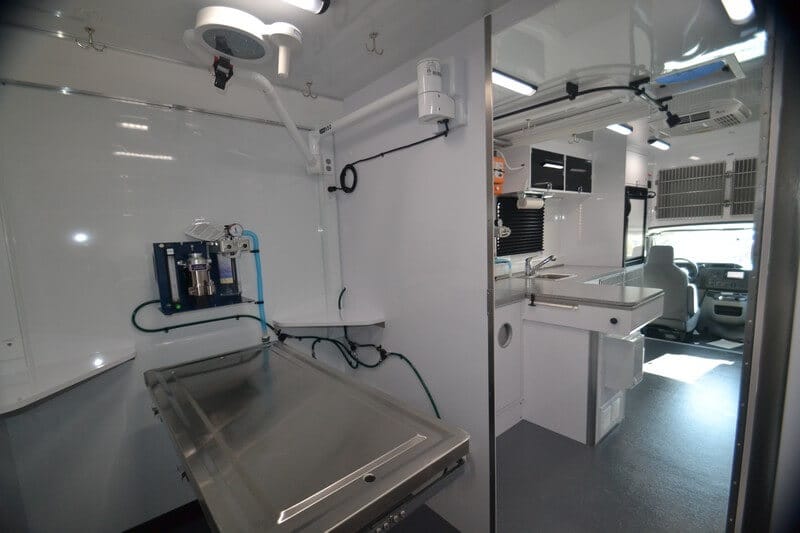 Interior of a mobile veterinary clinic, featuring an examination table, medical equipment, and a clean, organized workspace.